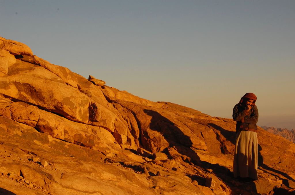 Person standing against a low rock formation in the desert