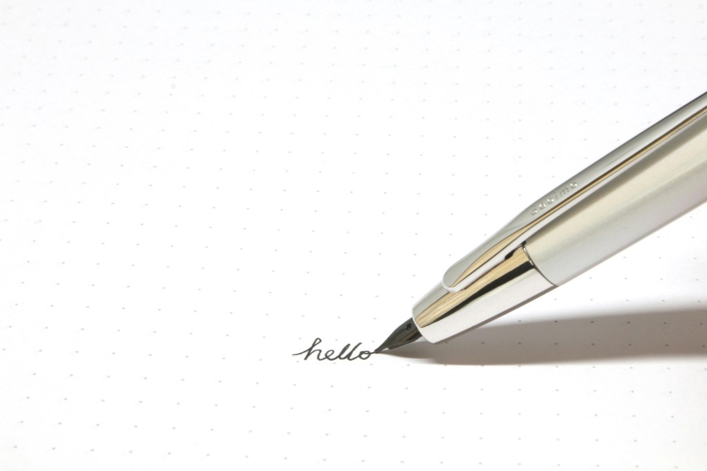 Fountain pen writing the word 'hello' on white paper