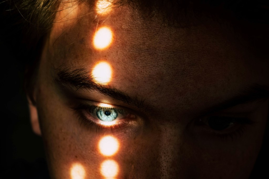 Close up of a face in the shadows with dots of light on the eye